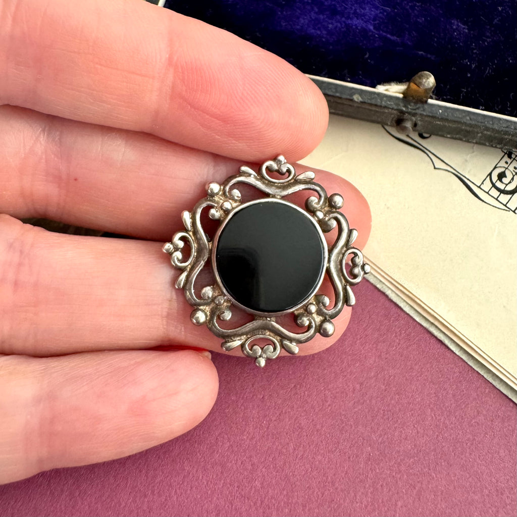 Vonk Jewellery sterling silver and black onyx brooch with a vintage postcard and jewellery box and in a woman's hand