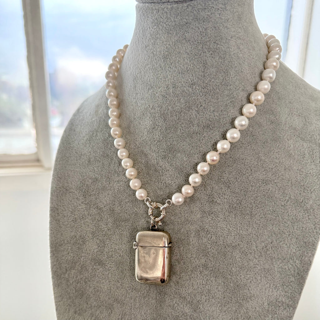 Pearl necklace with an antique silver vesta case pendant on a mannequin bust.