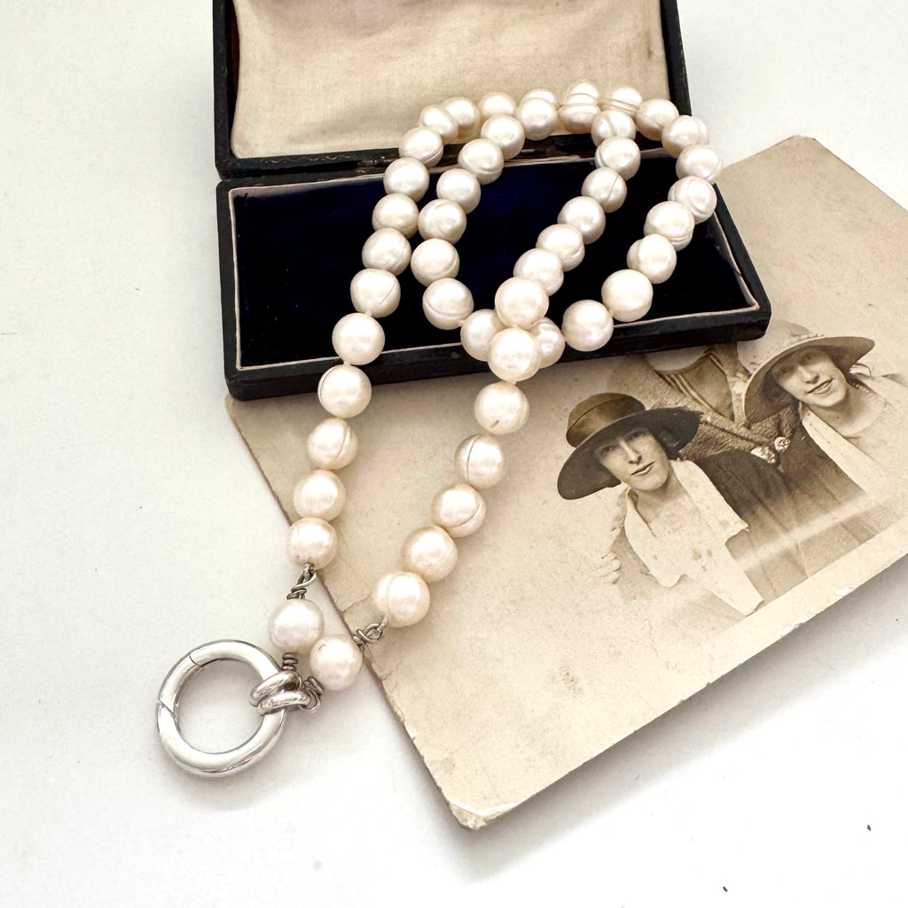 Pearl necklace with a clasp on an old photograph of two women.