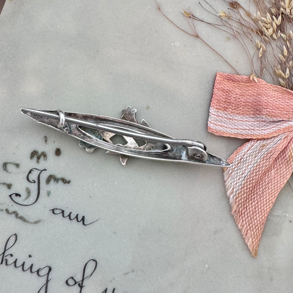 Back of Vonk Jewellery antique silver sweetheart brooch on a vintage postcard