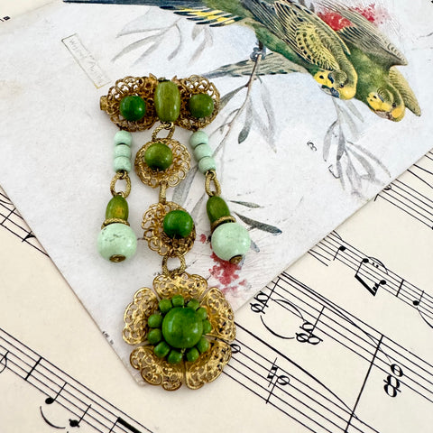 Vonk jewellery Made In Germany vintage gold tone and green bead dangle brooch on a vintage postcard and vintage sheet music