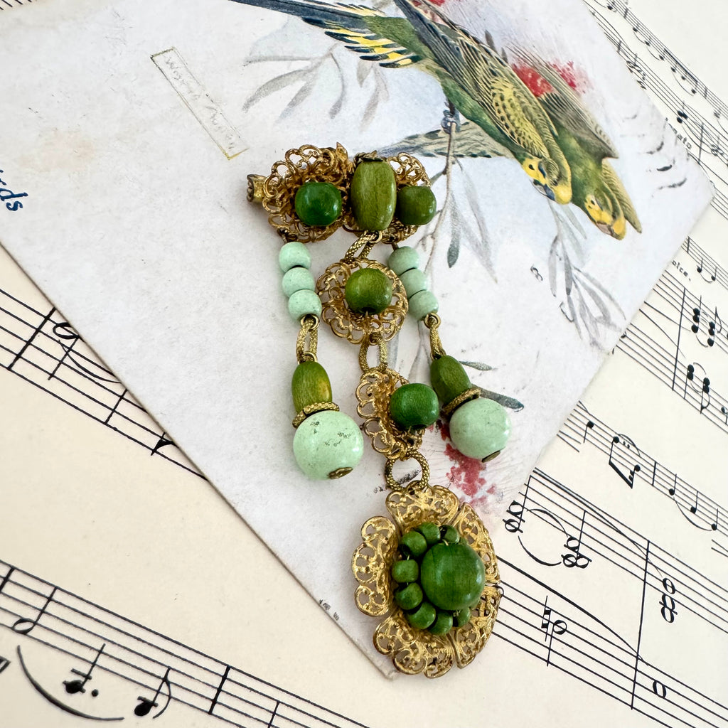 Vonk jewellery Made In Germany vintage gold tone and green bead dangle brooch on a vintage postcard and vintage sheet music