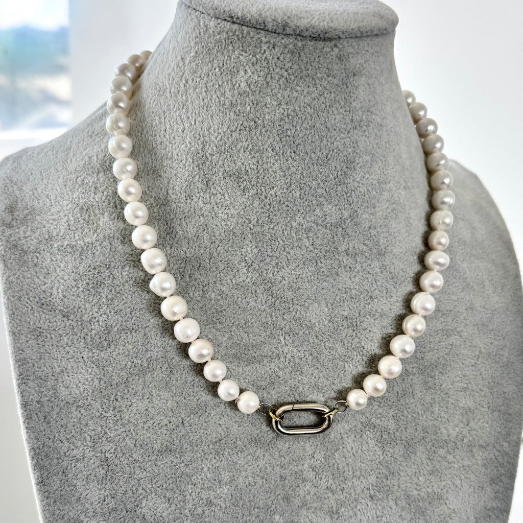 Pearl necklace on a gray mannequin bust with a blurred background