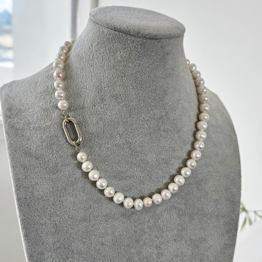 Pearl necklace on a gray mannequin bust with a blurred background