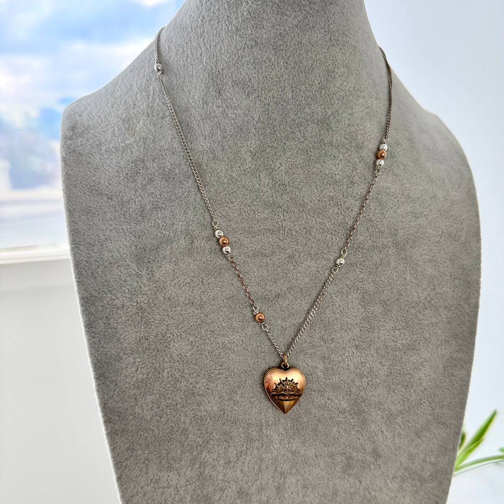 Necklace with a heart-shaped pendant on a gray mannequin bust against a light background