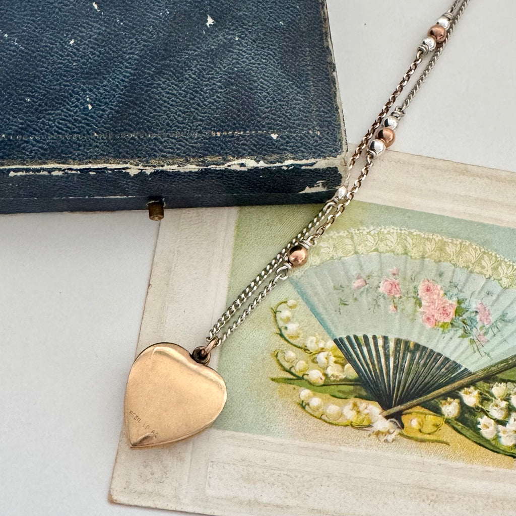 Back of WW2 ACMF heart-shaped pendant sweetheart locket on a chain against an old letter background