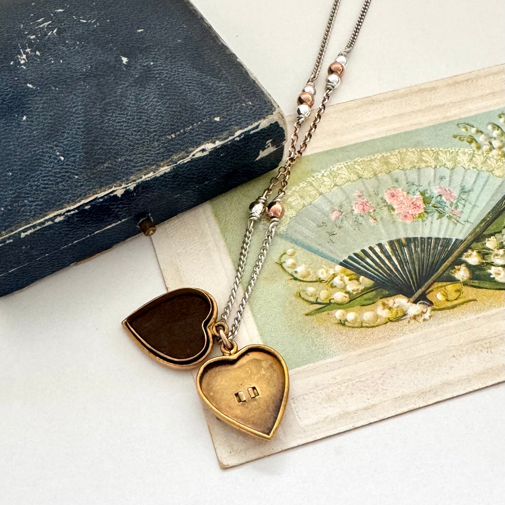 Open WW2 ACMF heart-shaped pendant sweetheart locket on a chain against an old letter background