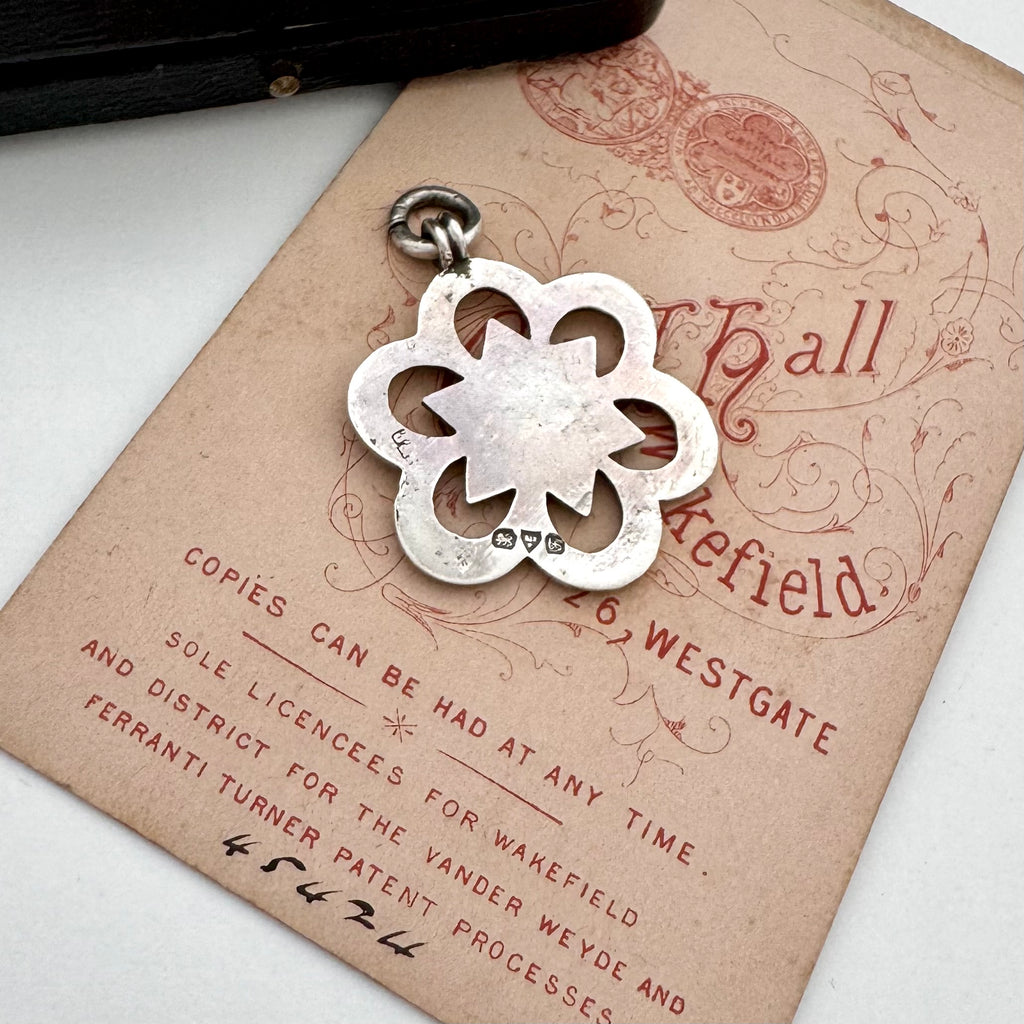 Silver floral antique watch fob pendant on an old document with a vintage feel