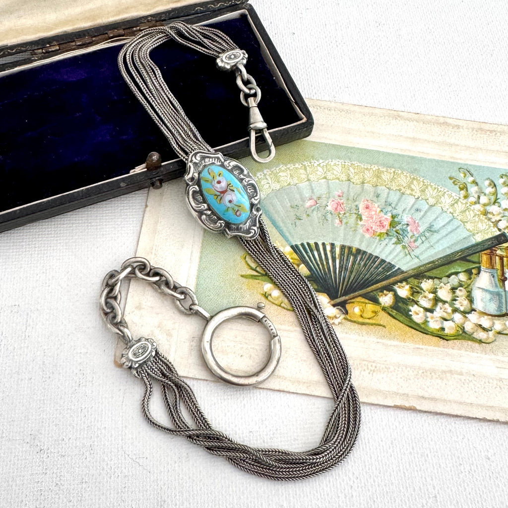 Antique French silver albertina chain with a turquoise and white stone pendant, displayed next to its dark velvet box and an antique-style fan illustration.