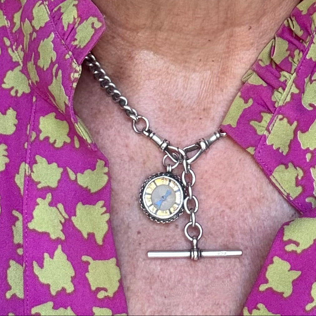 Antique watch chain and silver compass around a womans neck