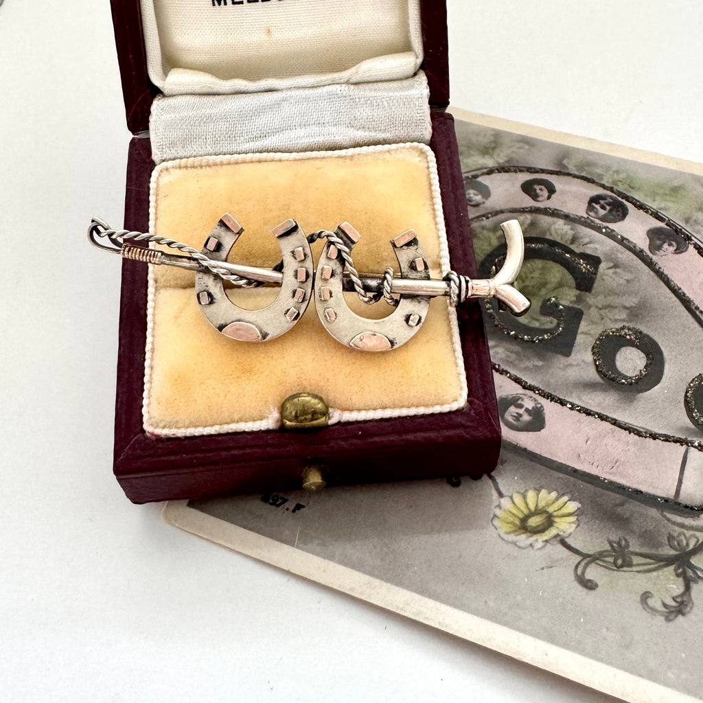 Antique silver horseshoe and riding crop brooch in a vintage jewellery box
