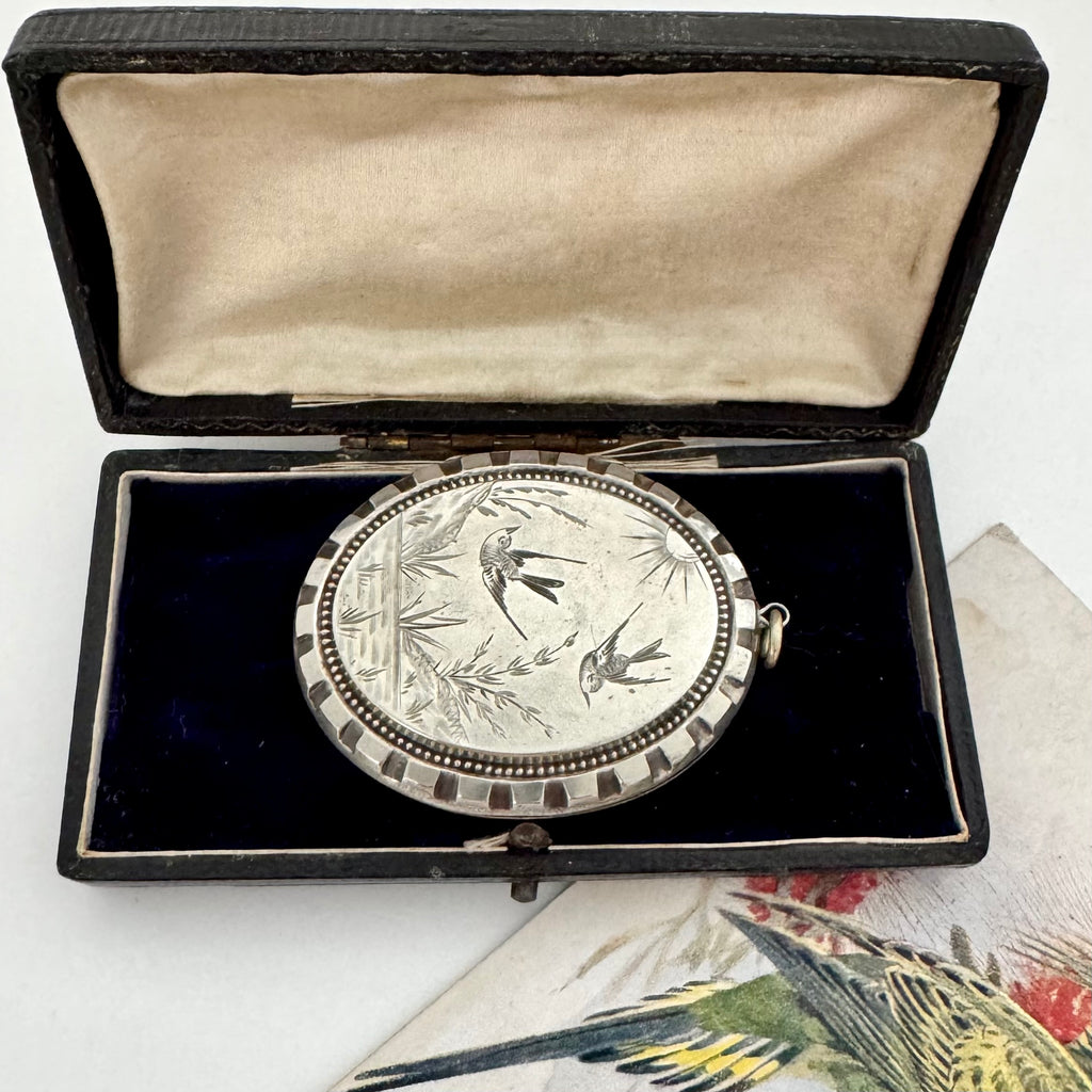 Silver Victorian aesthetic era locket in an open box on a white background