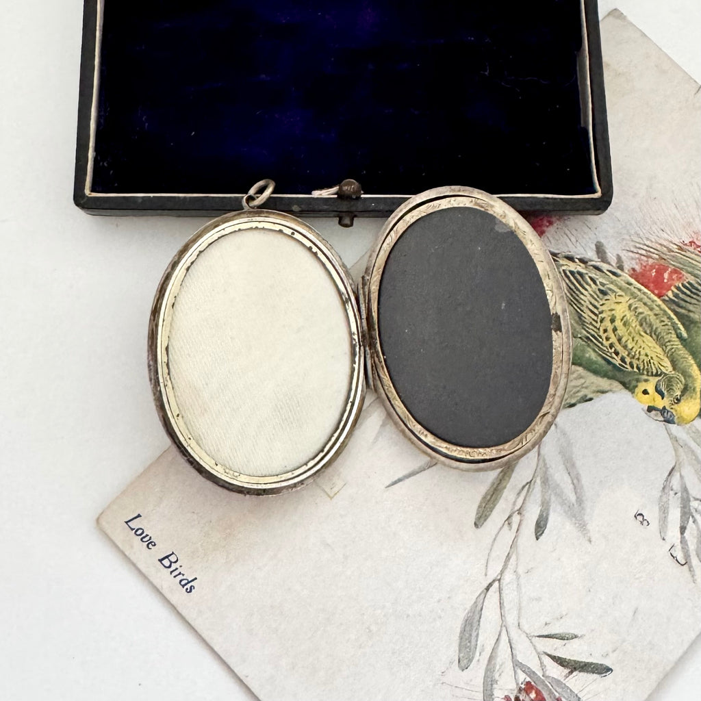 Open Victorian locket on a decorative surface with a 'Love Birds' card.