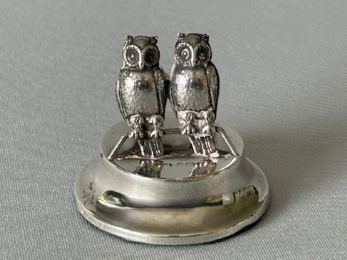 Silver owl-shaped object on a gray background