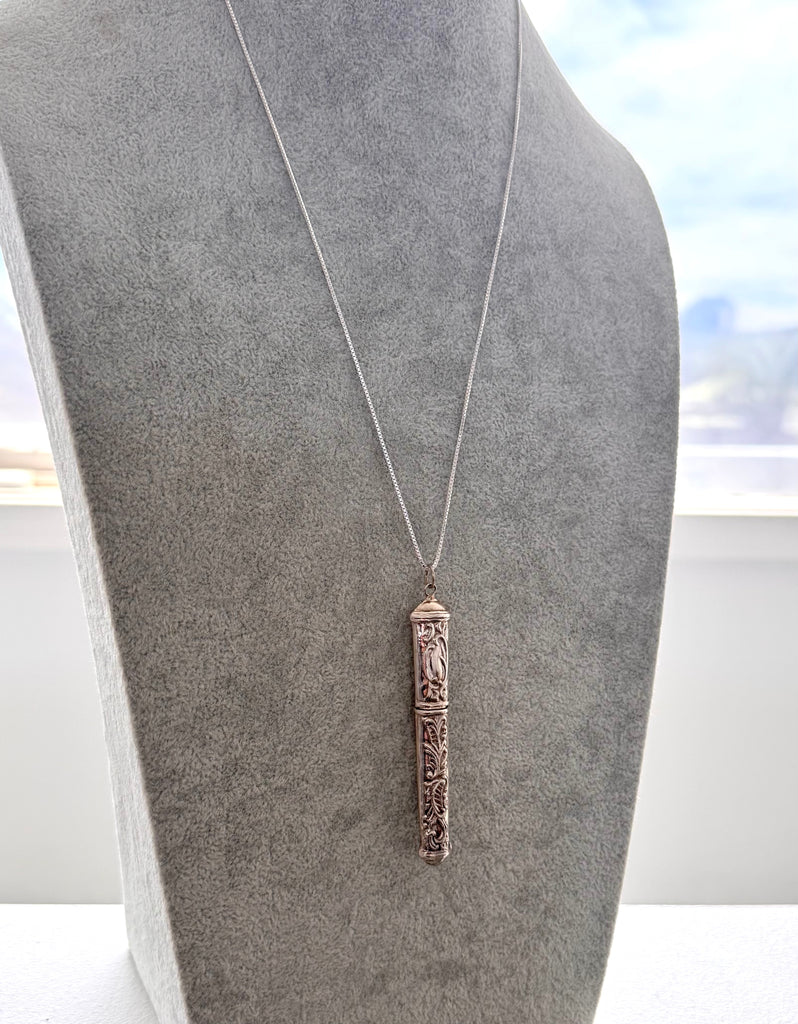 Vintage silver needle case on a grey mannequin