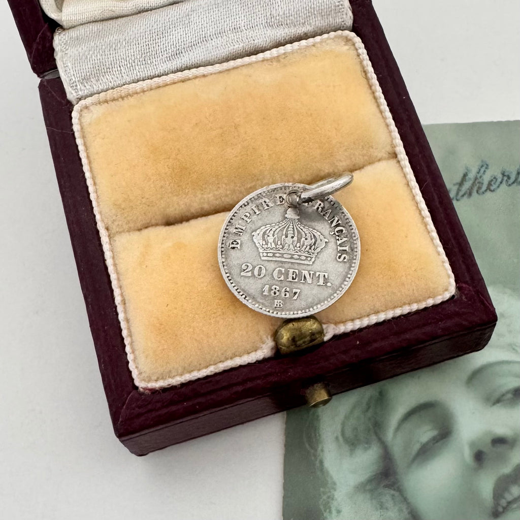 Silver coin with a crown and text in a wooden box on a white background