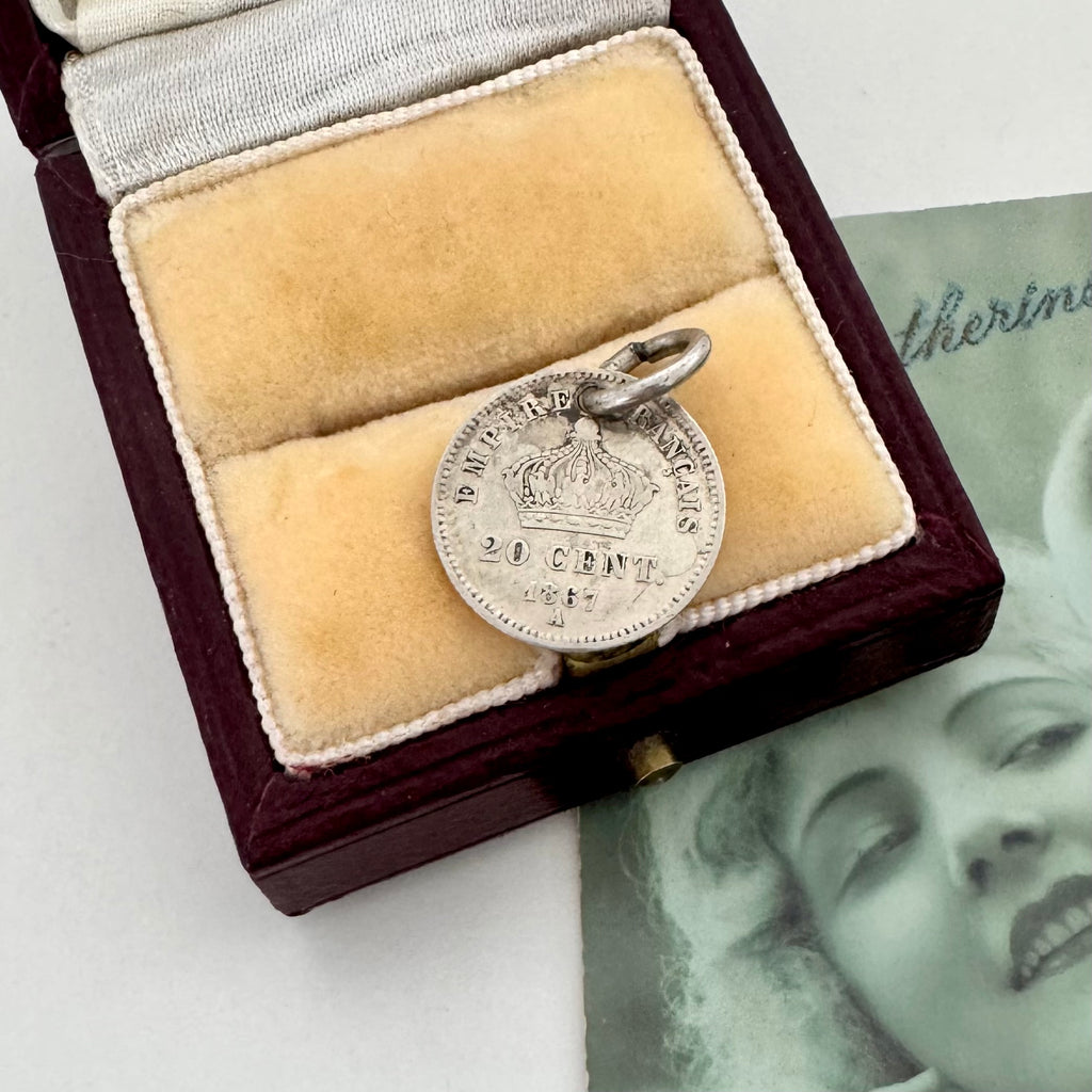 Silver coin with a crown design in a velvet-lined box on a white surface.
