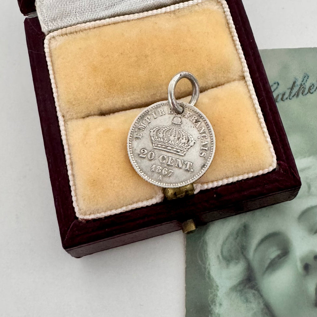 Silver coin pendant with a crown and '20 Cent' text in a wooden box with velvet lining.