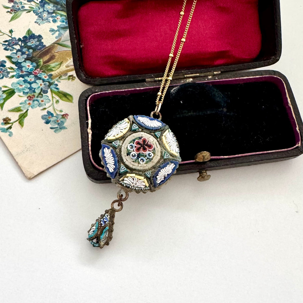 Decorative micro mosaic pendant necklace in a black velvet box with floral background
