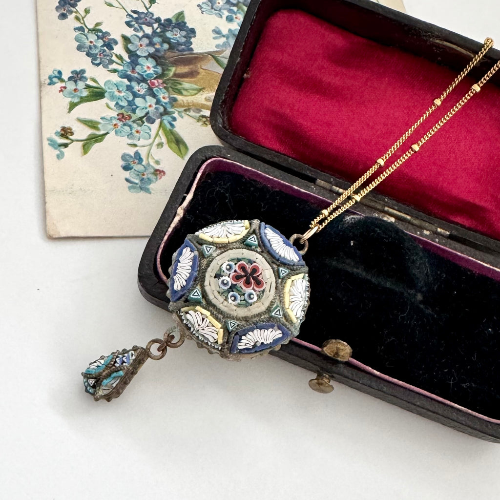 Decorative vintage micro mosaic necklace with intricate design in an open jewelry box on a white background