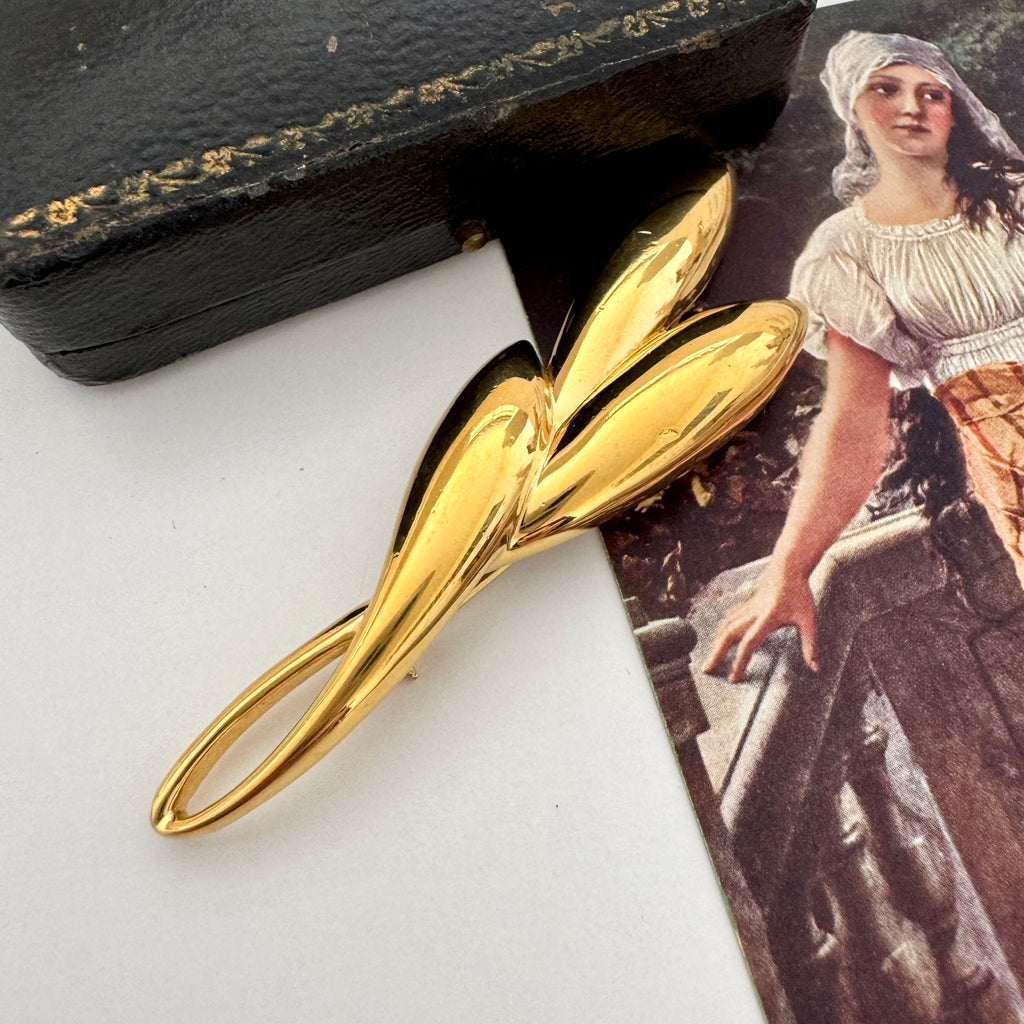 Vintage gold trifari brooch on a vintage postcard and with a vintage jewellery box in the background