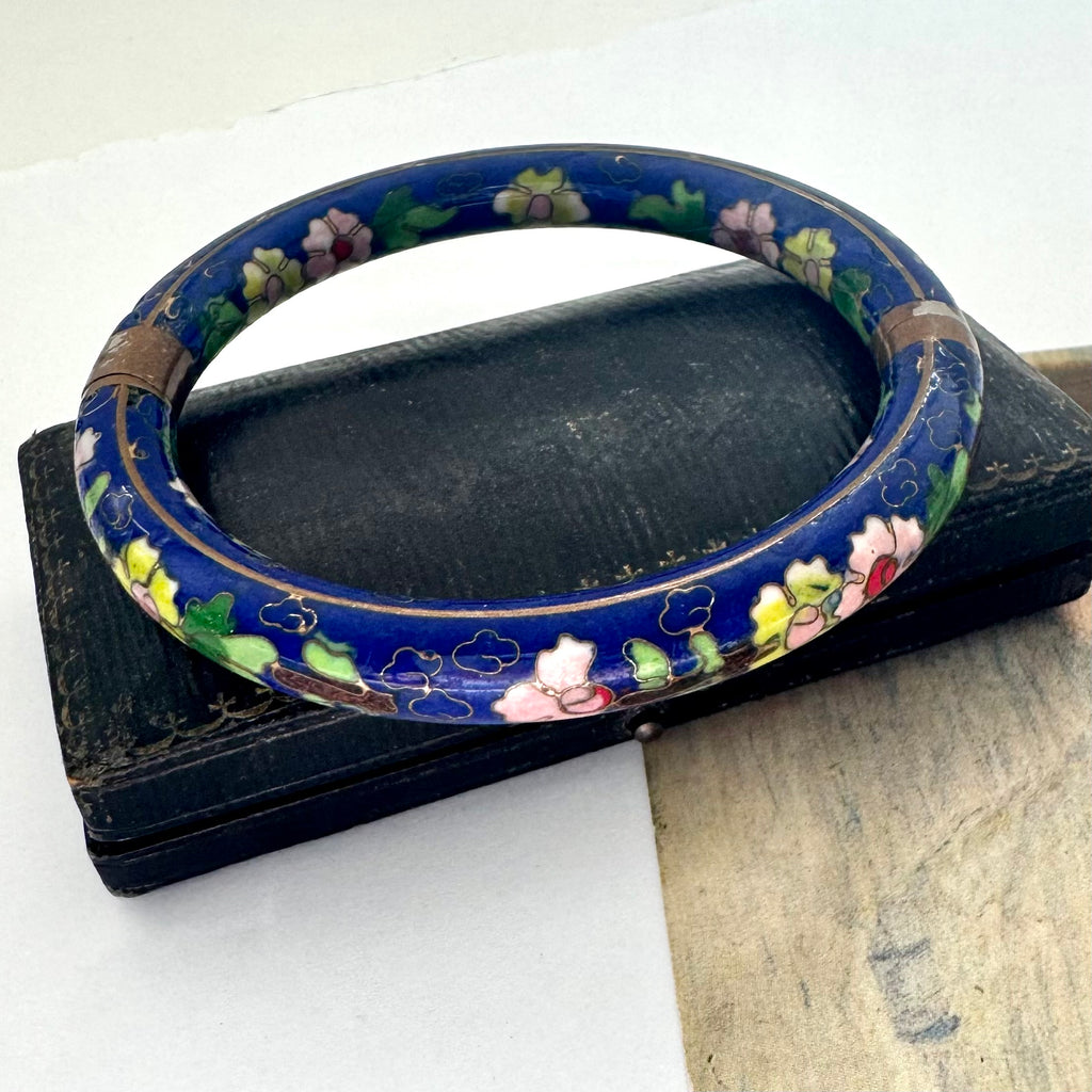 Decorative blue cloisonne bangle with floral patterns on a white background