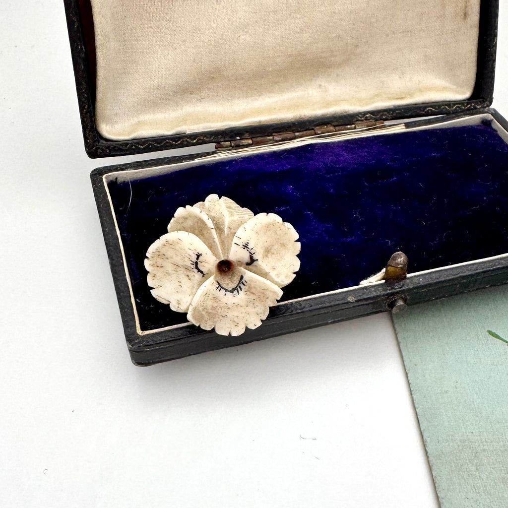 Vintage flower pansy brooch in an open jewelry box on a white background