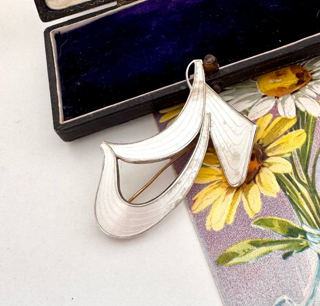 Silver Norwegian Ivar T Holth brooch on a floral card with an open jewelry box in the background