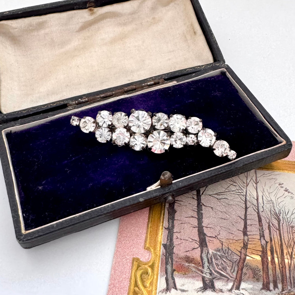 Vintage 1960's rhinestone brooch in a black box with a scenic postcard in the background