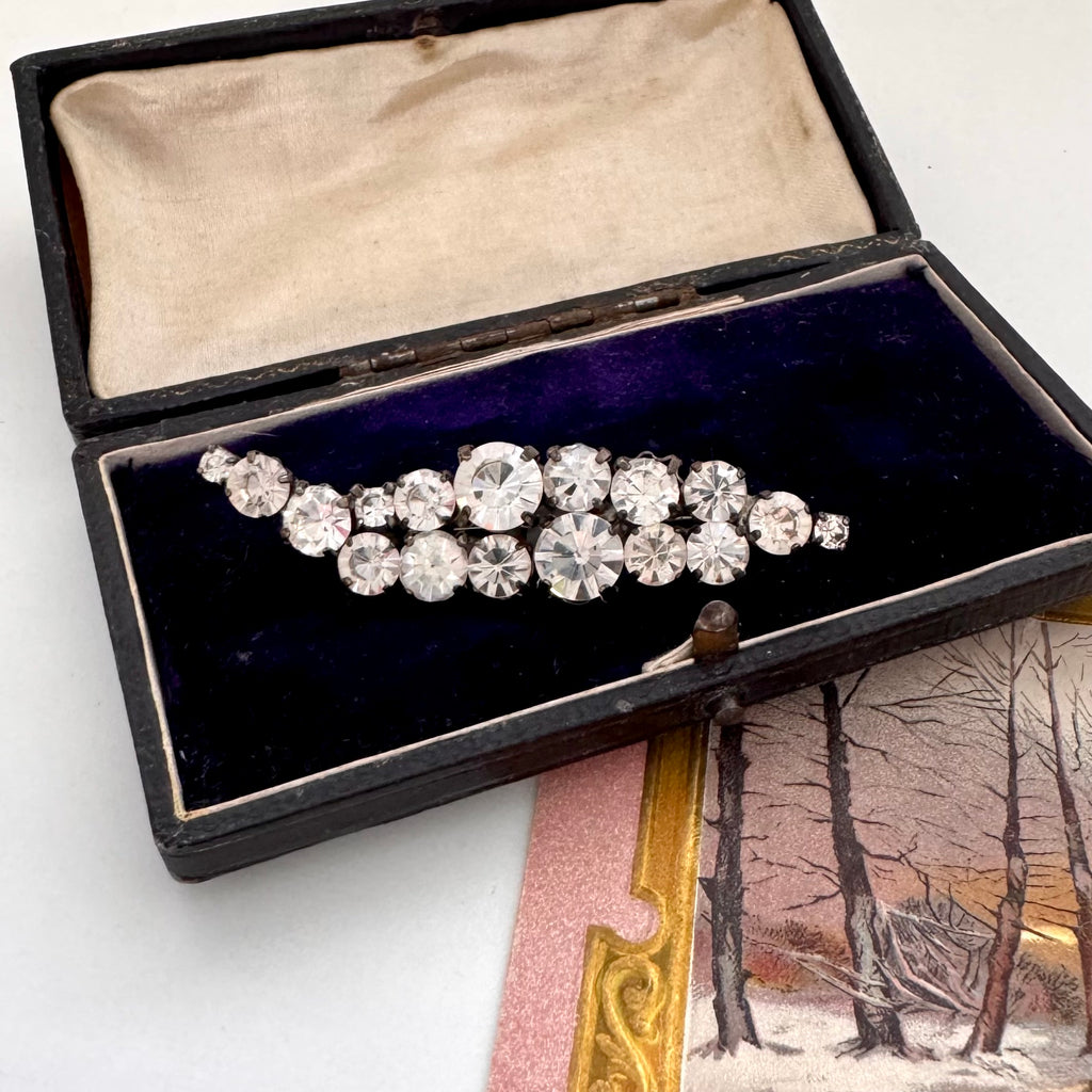Vintage 1960's rhinestone brooch in a black box with a scenic postcard in the background