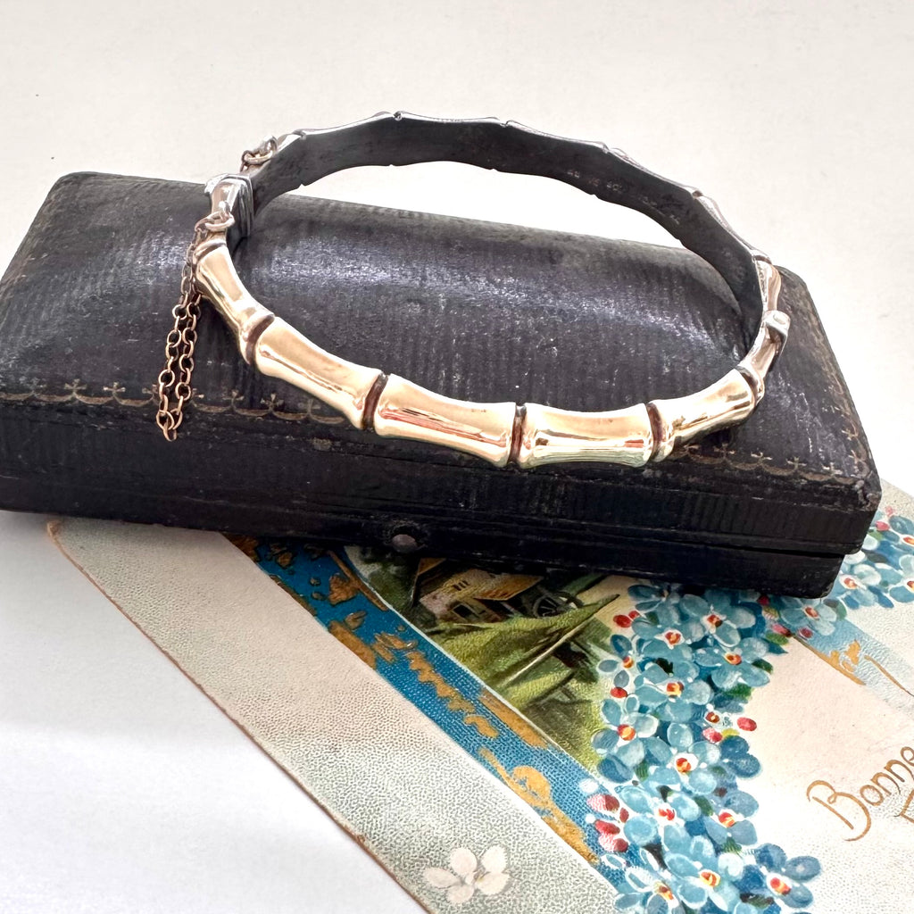 Vintage rolled gold on sterling silver bamboo-style bracelet on a black leather surface with a floral card underneath.