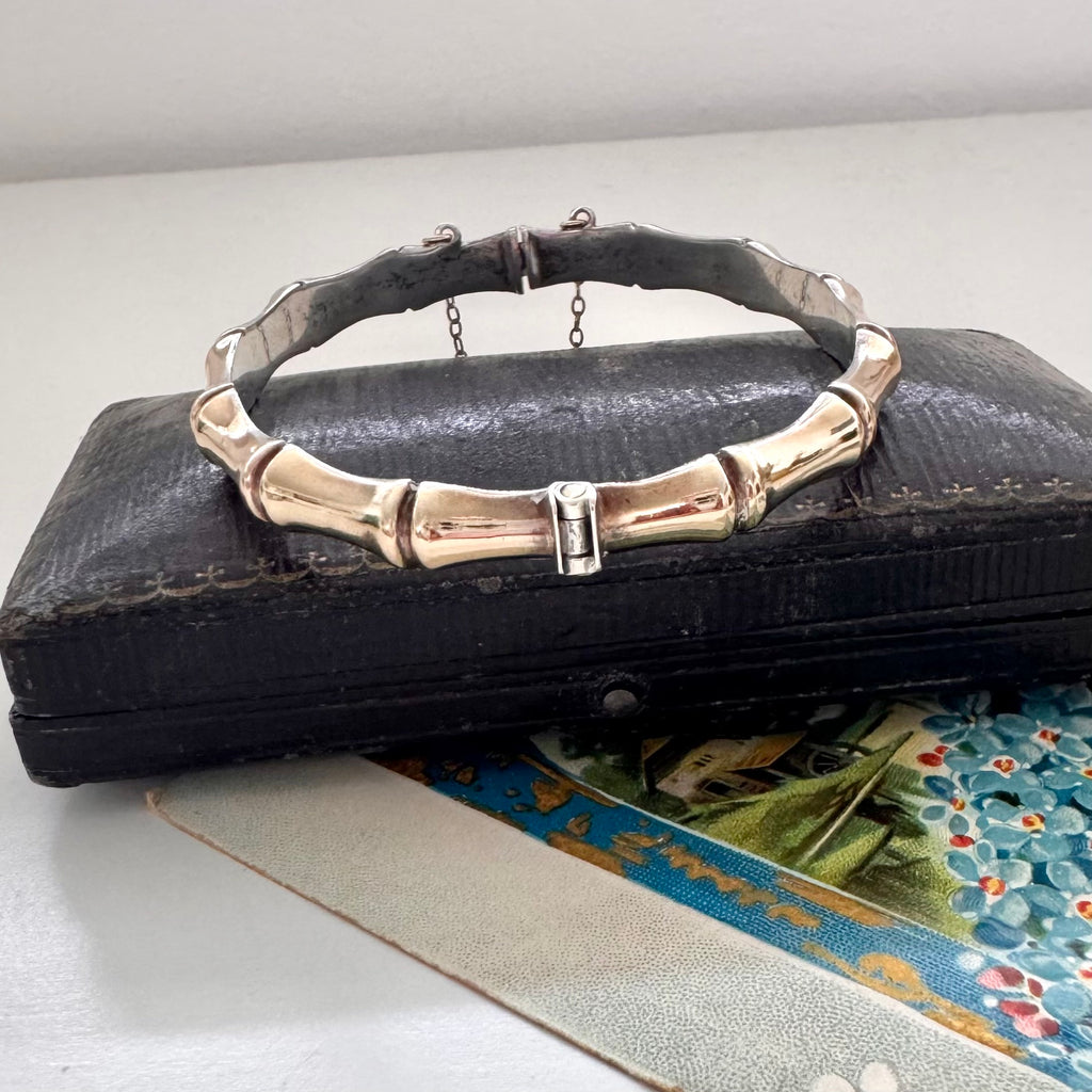Vintage rolled gold on sterling silver bamboo-style bracelet on a black leather surface with a floral card underneath.