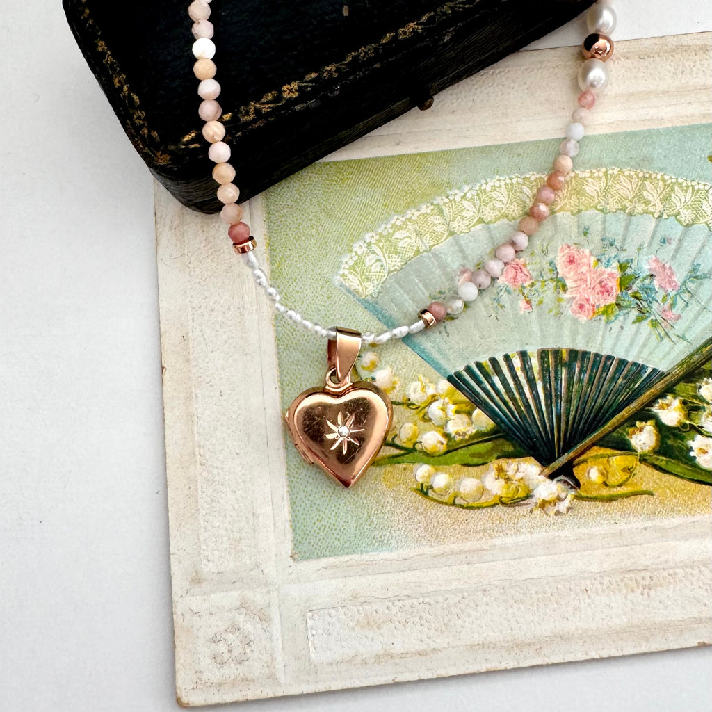 Necklace with a heart pendant on a decorative card with flowers and a fan.