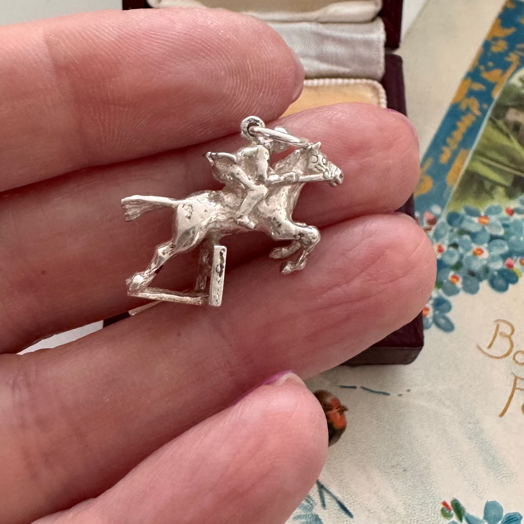 Vintage silver equestrian charm in a woman's fingers.