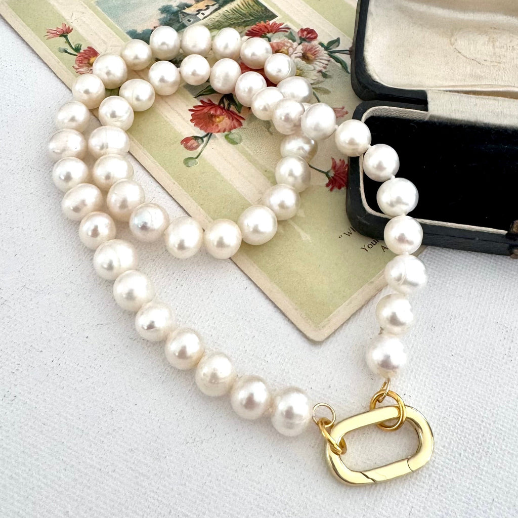 White pearl and gold neckalce on an old postcard and near an old jewellery box