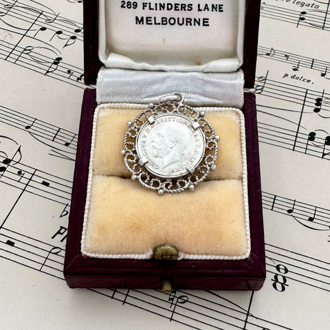 Antique 1918 silver threepence charm or pendant in a box on sheet music