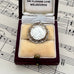 Antique 1918 silver threepence charm or pendant in a box on sheet music