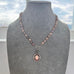 Pearl necklace and 1933 watch fob with a silver clasp on a grey mannequin