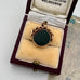 9ct  rose gold antique swivel fob with a dark stone in a jewelry box on a textured surface