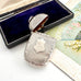 Antique 1879 Victorian silver vesta case on a white background with a vintage postcard and old box in the background.