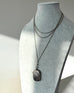 Necklace with an antique vesta case on a mannequin bust against a neutral background