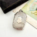 Antique 1879 Victorian silver vesta case on a white background with a vintage postcard and old box in the background.