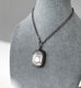 Silver antique watch chain necklace with a n antique vesta case pendant on a mannequin bust against a gray background