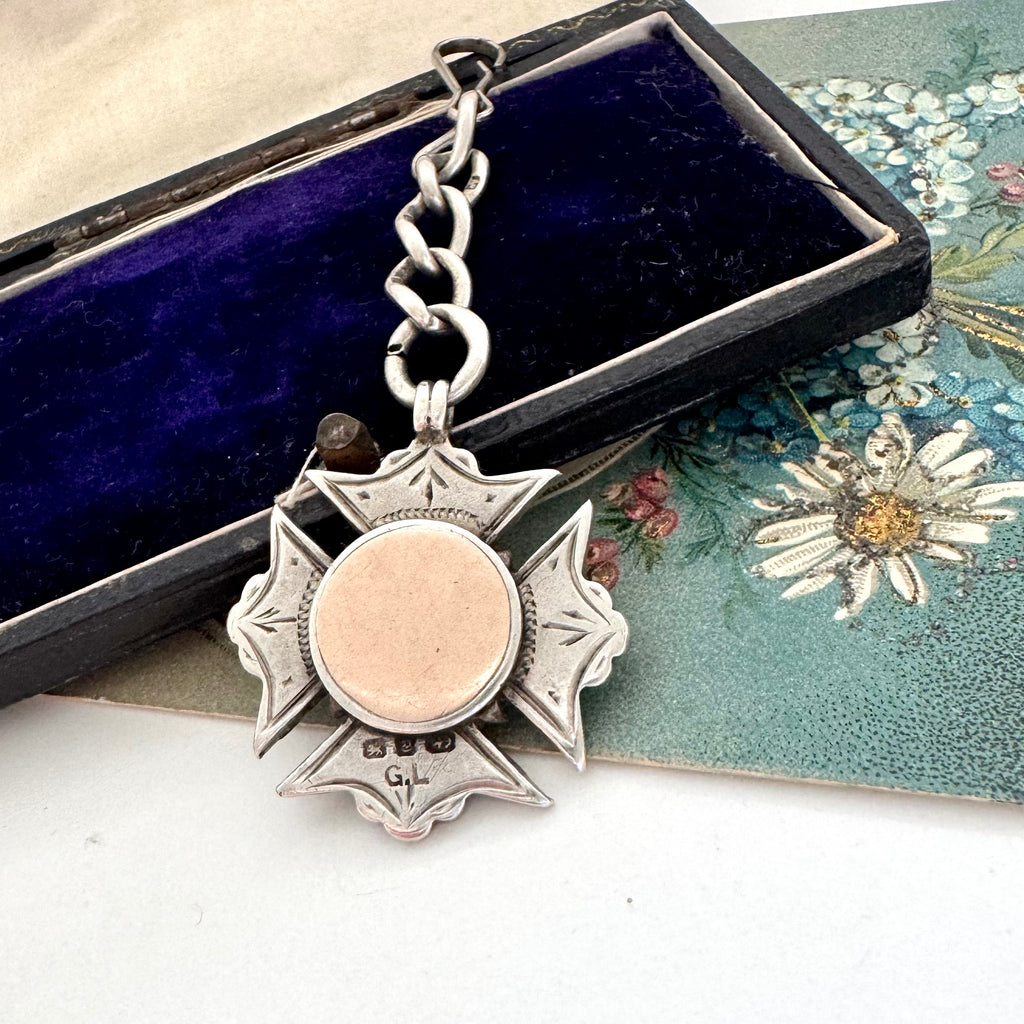 Antique 1898 sterling silver watch fob and chain on an old jewellery box and with an old postcard