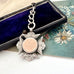 Antique 1898 sterling silver watch fob and chain on an old jewellery box and with an old postcard