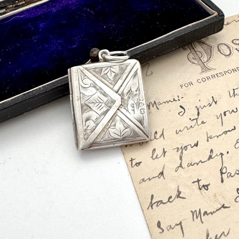 Antique silver stamp case with intricate design on a vintage letter