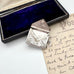 Antique silver stamp case with intricate design on a vintage letter