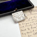 Antique silver stamp case with intricate design on a vintage letter