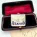 Antique 1911 Crisford & Norris silver stamp case with 'STAMPS' in blue enamel in a black box with red interior.