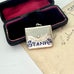 Antique 1911 Crisford & Norris silver stamp case with 'STAMPS' in blue enamel in a black box with red interior.